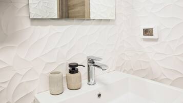Une salle de bain avec un lavabo blanc, un robinet chromé et un mur à texture.