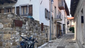 Una estrecha calle adoquinada con muros de piedra y balcones de madera.