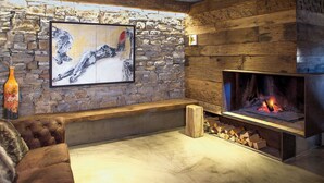 Una sala de estar acogedora con una pared de piedra, una chimenea y un cuadro abstracto grande.