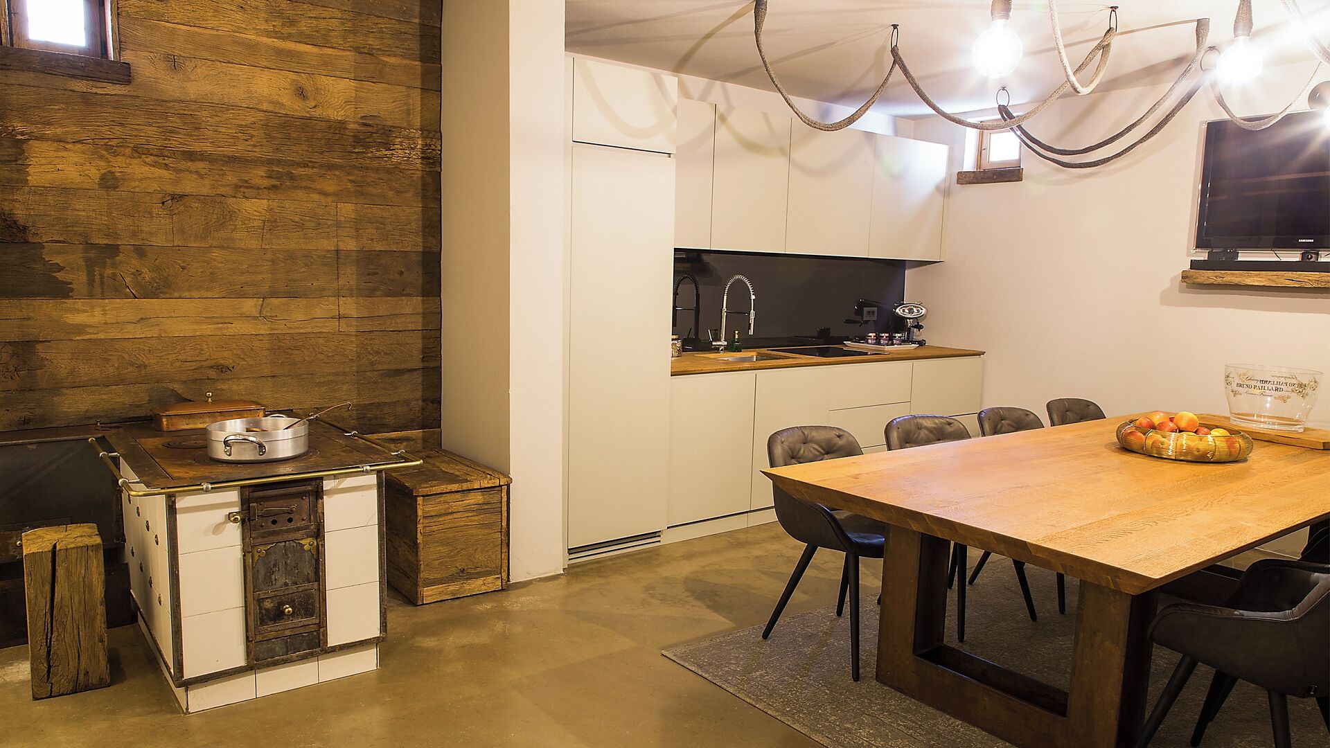 Une cuisine compacte dotée d’un plan de travail en bois, d’un évier et d’un coin repas avec une table et des chaises en bois.