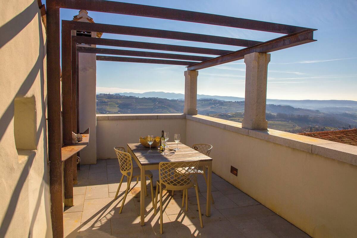 Un balcon avec une table et des chaises, donnant sur un paysage pittoresque.