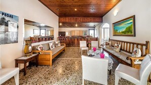 A spacious living area with a wooden ceiling, a kitchen in the background, and a bar area. - HARMONY HOTEL AND STUDIOS (Hersonissos)