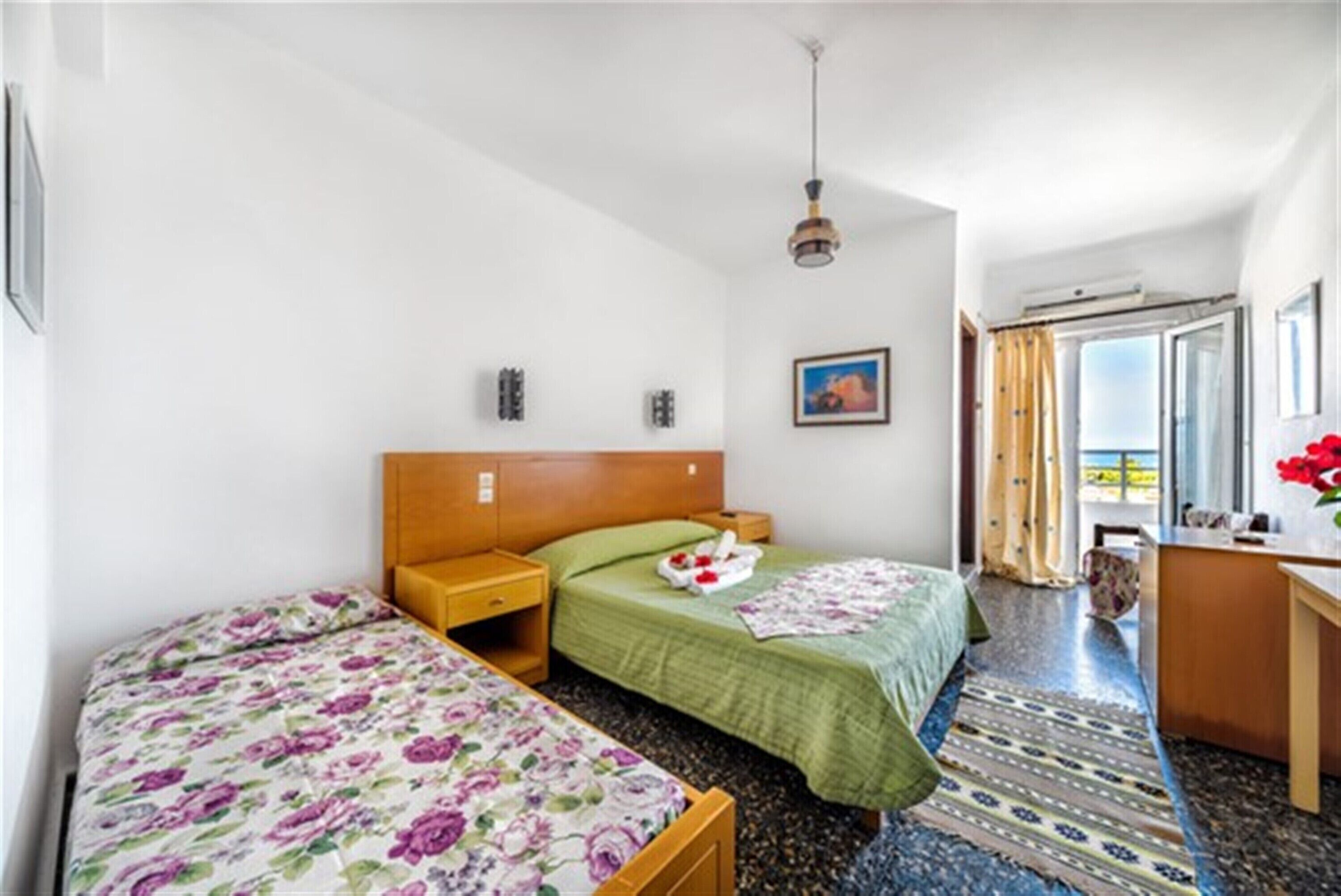 Habitación de hotel con dos camas, un escritorio y una ventana con cortinas.