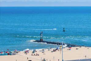 Una playa con un rompeolas rocoso, sombrillas y gente tomando el sol.