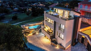 Une maison moderne à deux étages, dotée d’une piscine, d’un espace de détente extérieur et offrant une vue sur le paysage environnant.