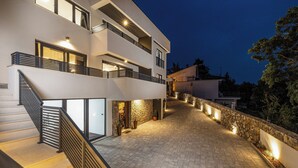 Un bâtiment moderne à plusieurs étages, doté d’un escalier, d’un mur en pierre et d’un éclairage extérieur.