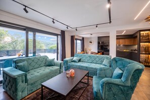 A modern living room with a sofa set, a coffee table, and a kitchen area with cabinets and a wine rack. - Pool & Wellness Villa Betelgeuse Supernova (Novi Vinodolski)