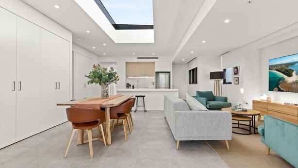 A modern kitchen with white cabinets, a central island, and a skylight above. - Allura Escapes by Experience Jervis Bay (Huskisson)