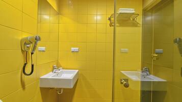 Een badkamer met gele wanden, twee wastafels, een haardroger en een handdoekhouder.