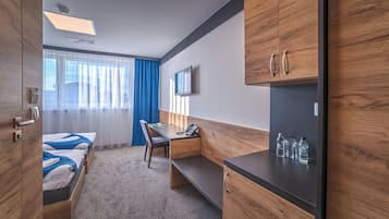 Una habitación de hotel con cama, escritorio, silla, televisor y minibar.