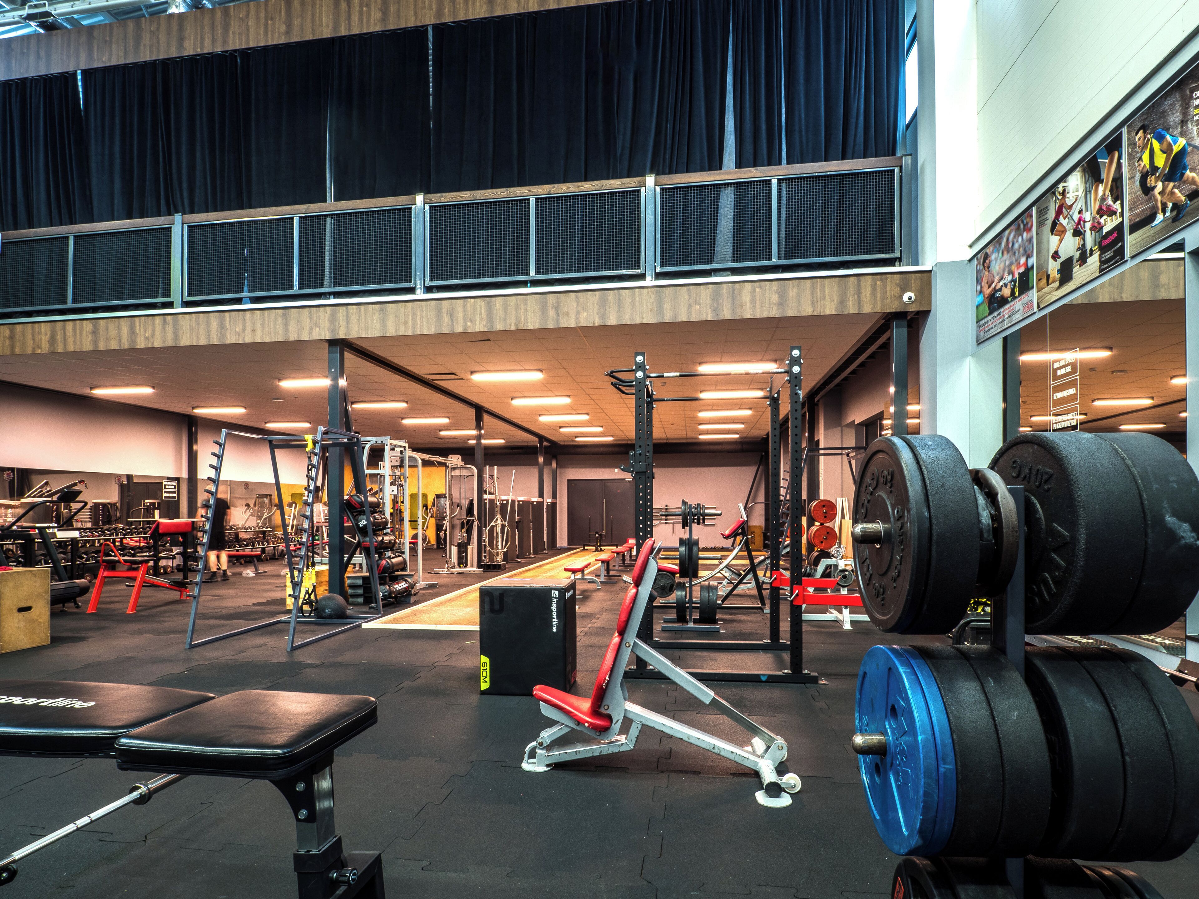 A gym with various exercise equipment, including weight benches, dumbbells, and a squat rack.