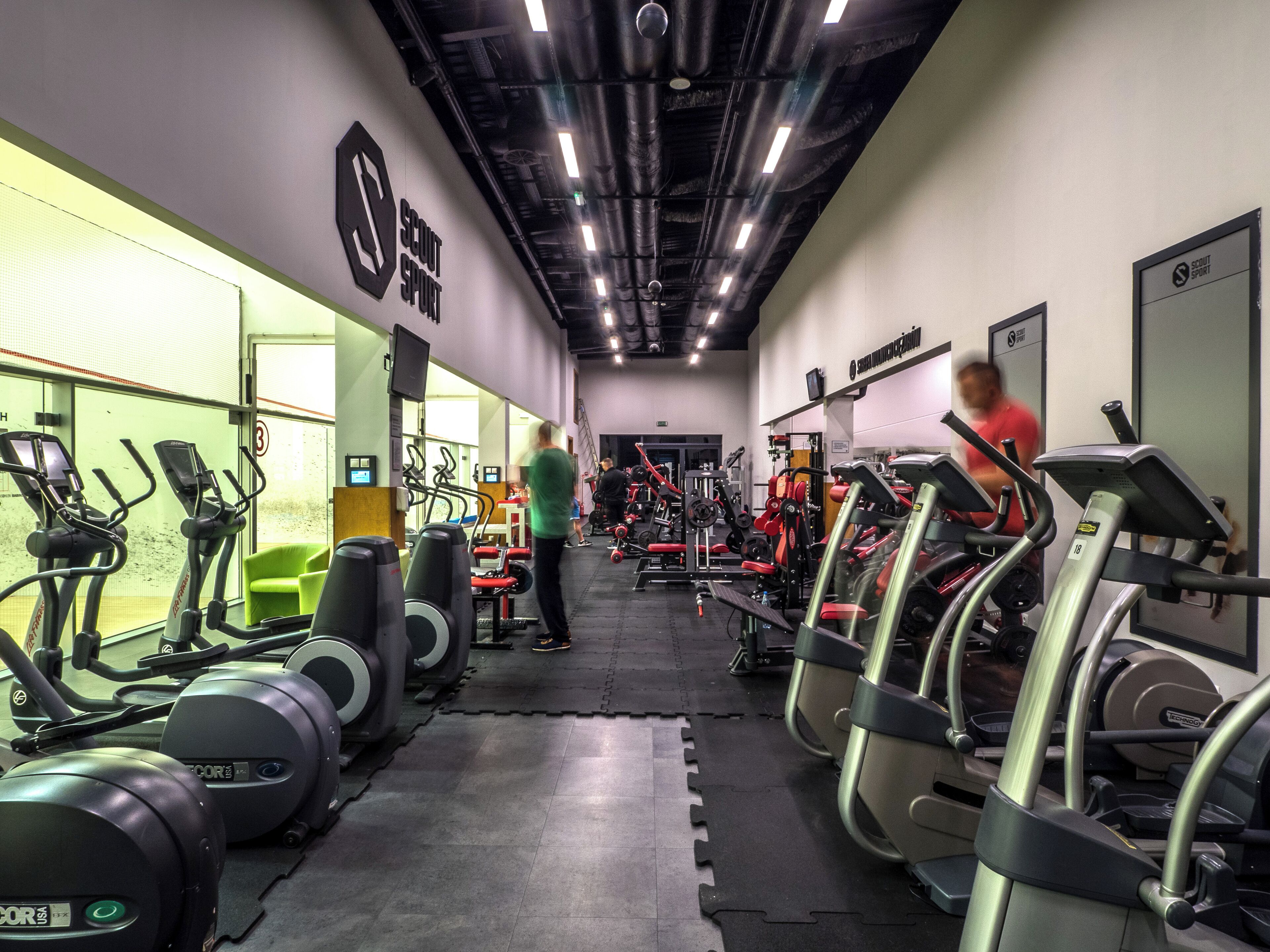 Un gimnasio con cintas de correr, máquinas de pesas y colchonetas de ejercicio.