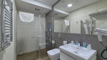 A modern bathroom with a glass shower enclosure, a white sink with toiletries, and a towel rack with a baby foot towel.