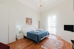 A bedroom with a bed, bedside table, lamp, and a TV. - Marsala Suites - AW Farm (Marsala)