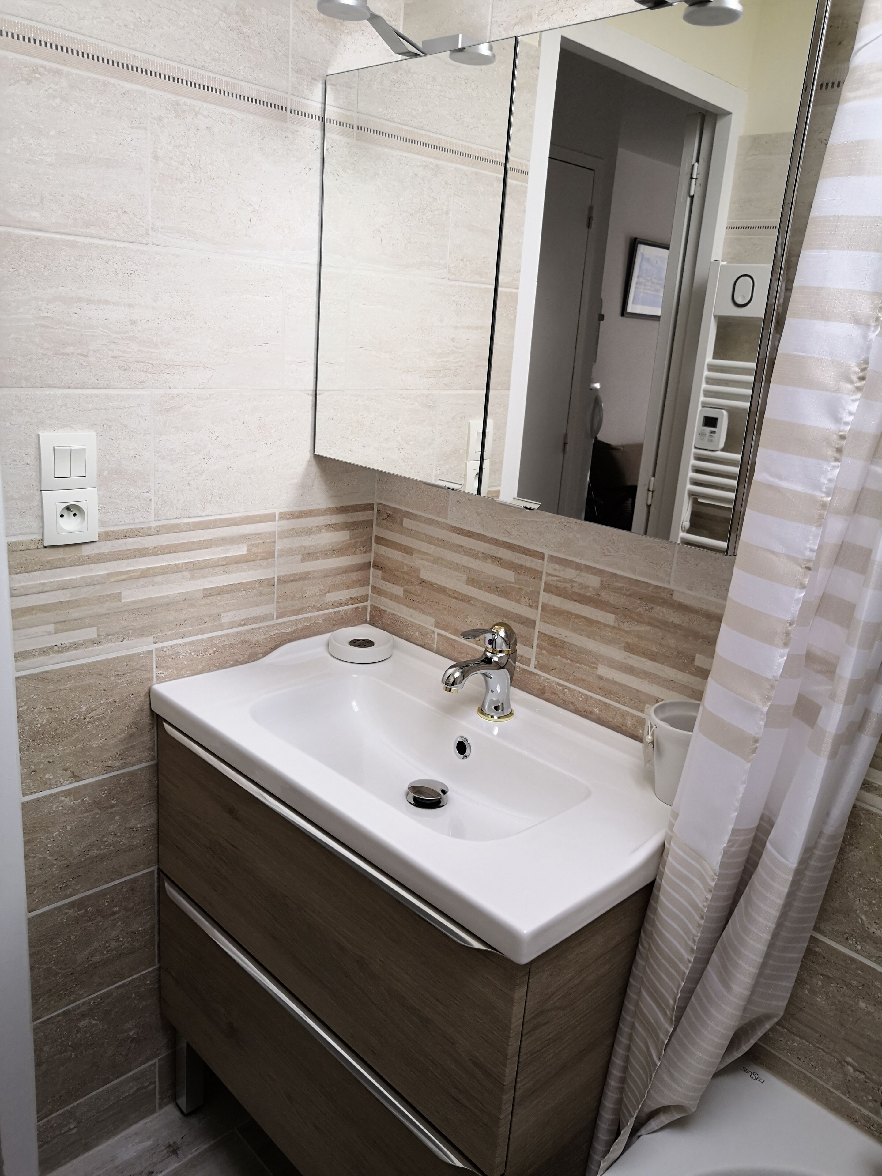 A bathroom with a white sink, a mirror, and a shower curtain.