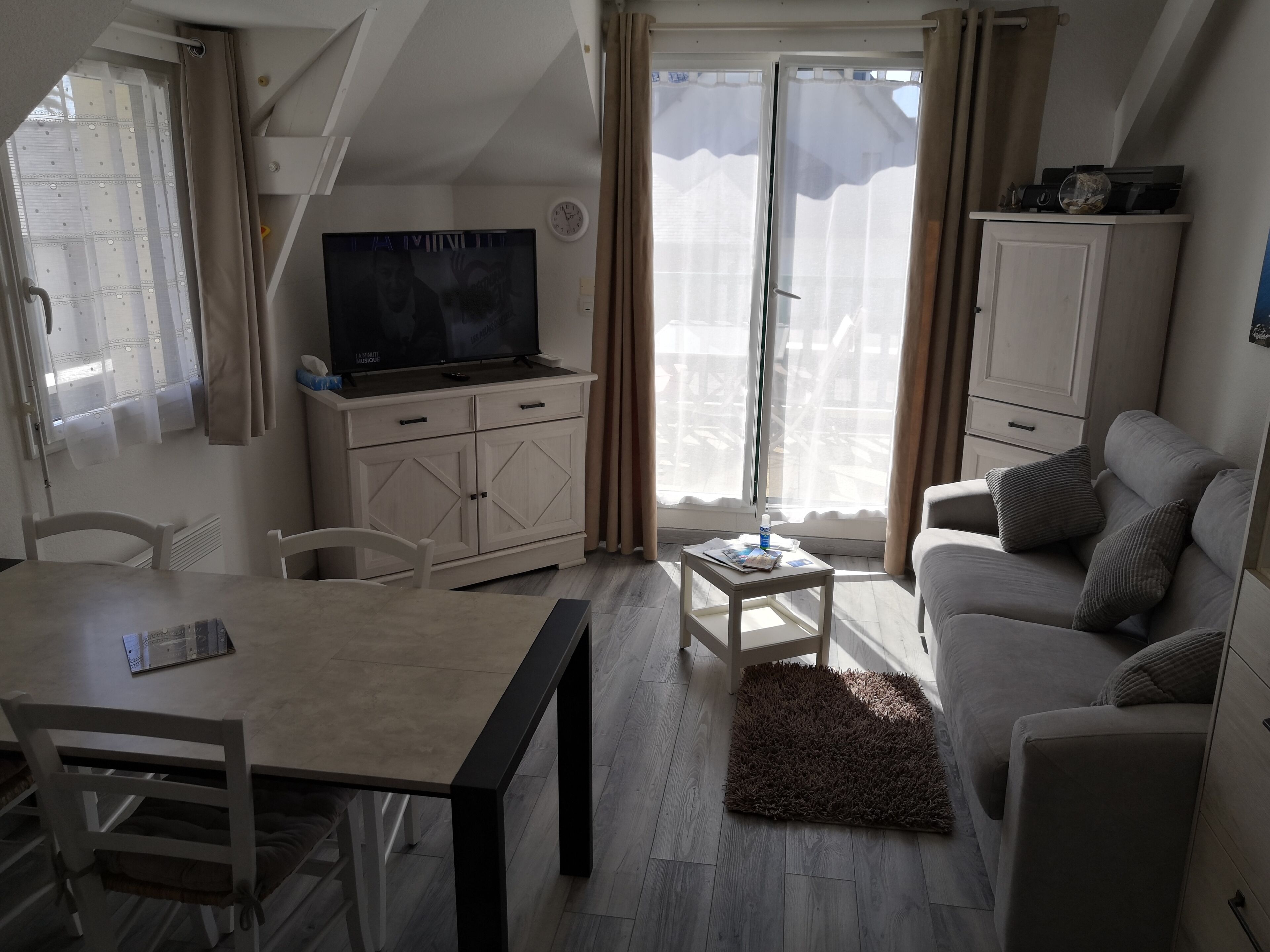 A compact living space with a dining table, a sofa, a television, and a cabinet.