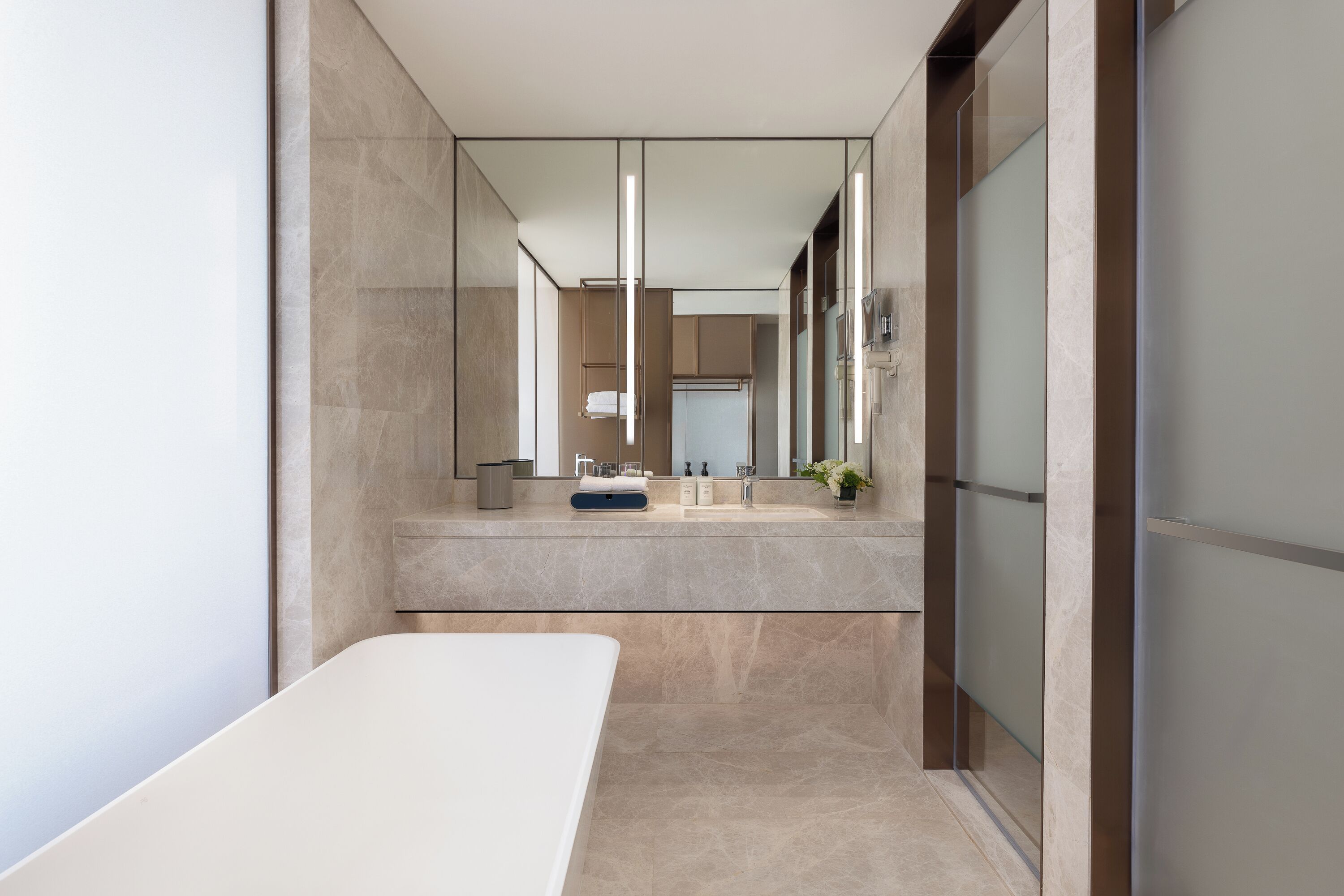 Een moderne badkamer met een grote spiegel, een ligbad en een wastafelmeubel met een handdoekhouder.