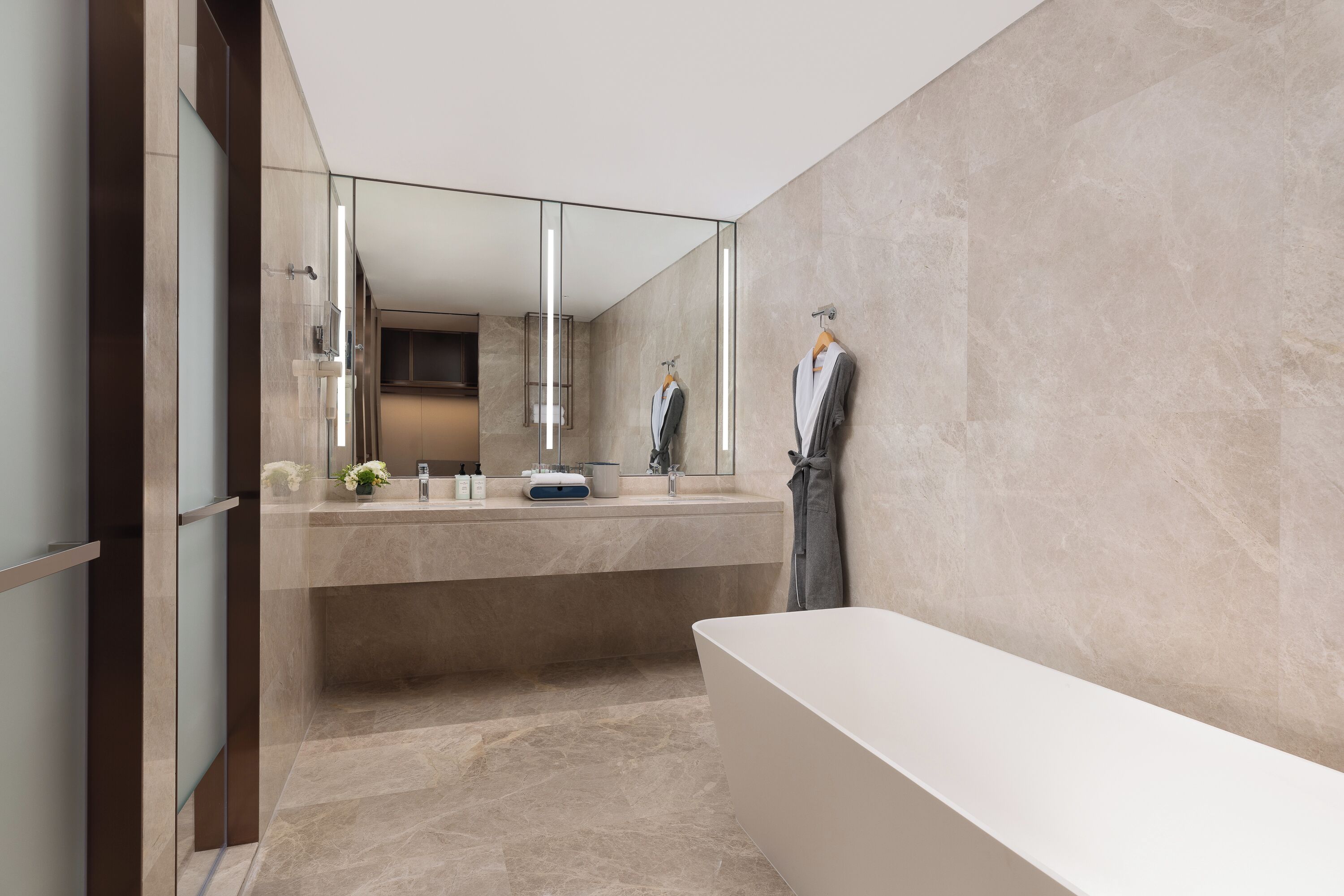 Ein modernes Badezimmer mit einem großen Spiegel, einer Badewanne und einem Waschtisch mit Spüle und Handtuchhalter.