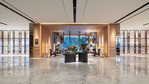A spacious lobby with a polished marble floor, two large black planters with flowers, and a view of the city through large windows. - The Perennial Tianjin, A JdV by Hyatt Hotel (Tianjin)
