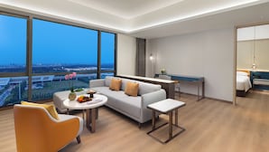 A modern hotel room with a large window, a sofa, a dining table, and a small kitchen area. - The Perennial Tianjin, A JdV by Hyatt Hotel (Tianjin)