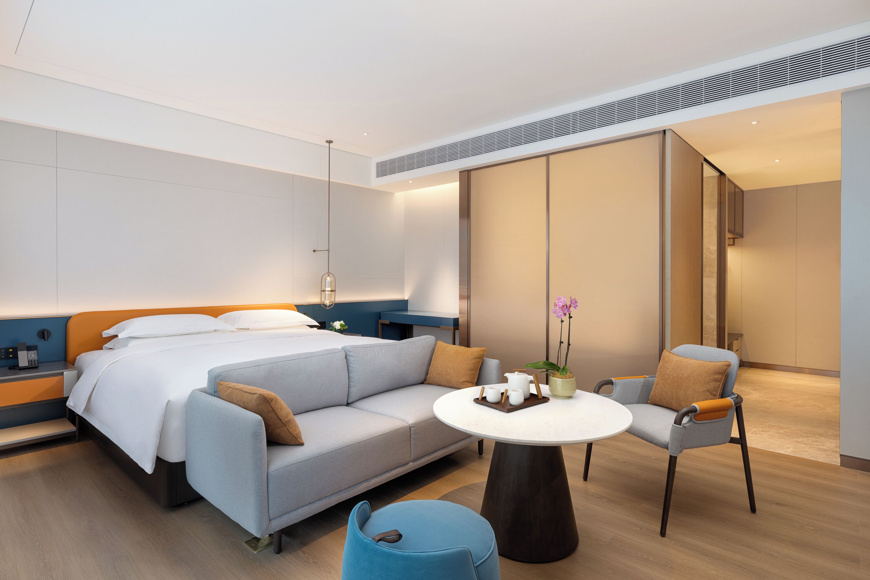 Una habitación de hotel moderna con cama, sofá y una pequeña mesa de comedor.