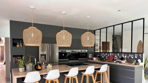 A modern kitchen with a central island, bar stools, and hanging wicker light fixtures. - Magnificent house on the Côte Bleue, 2 steps from the calanques! (Le Rove)