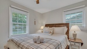 Un dormitorio con una cama, dos lámparas de noche, un reloj y una ventana con persianas.