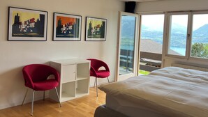 A bedroom with a bed, two red chairs, a white desk, and three framed artworks on the wall. - die Villa", Eine Wohnung für 6 Personen (Sigriswil)
