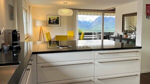 A modern kitchen with a large island, white cabinetry, and a view of mountains. - die Villa", Eine Wohnung für 6 Personen (Sigriswil)