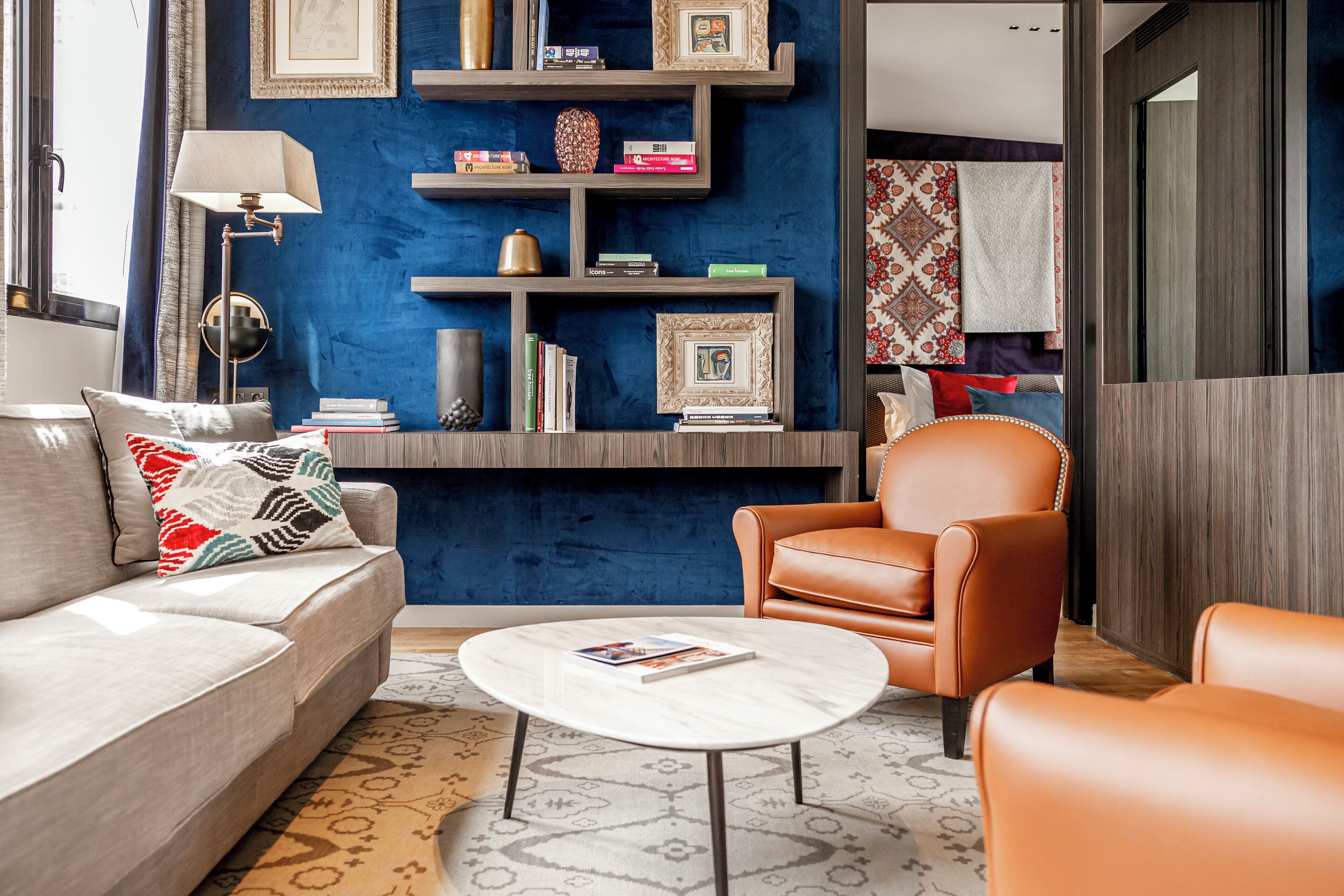 A modern living room with a blue accent wall, a sofa, a coffee table, and a leather armchair.