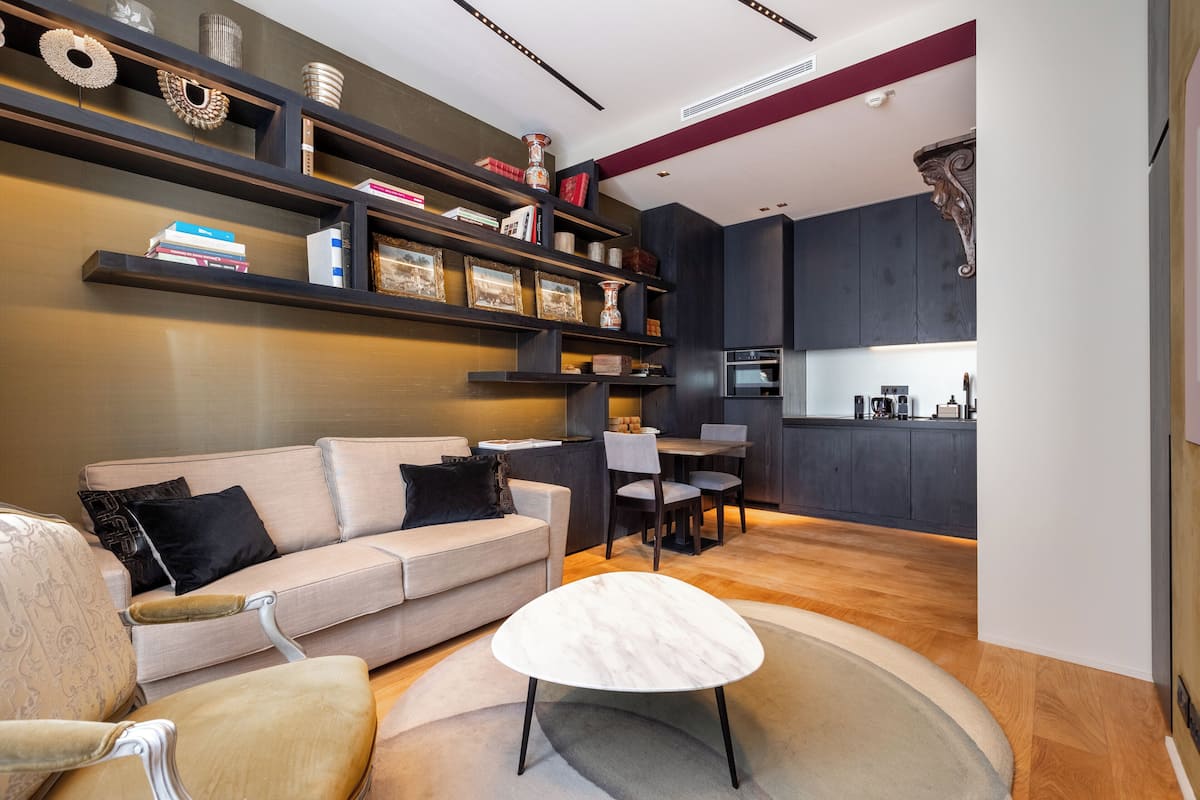 A modern living room with a sofa, chairs, a coffee table, and a kitchen area with a dining table and chairs.