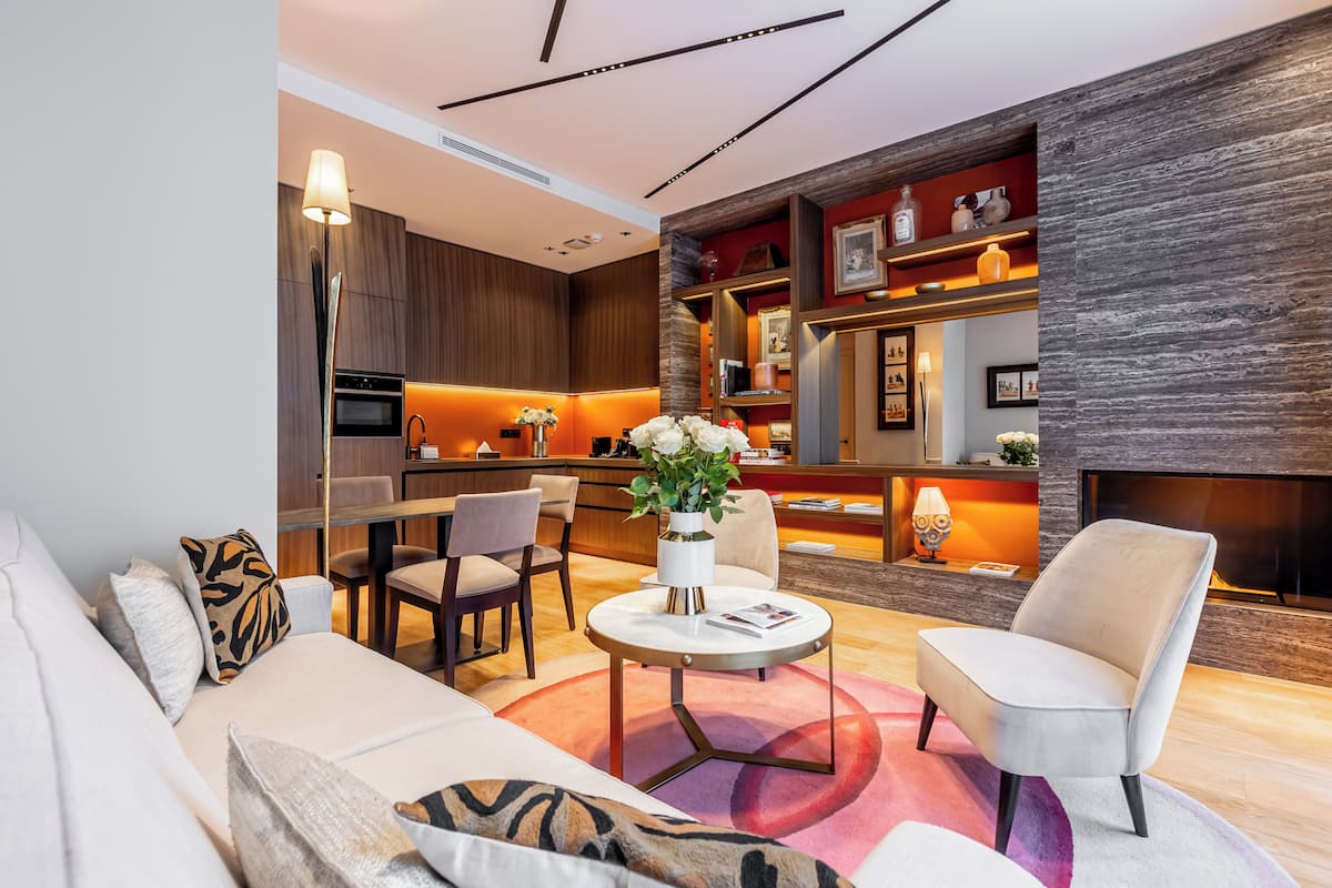 A modern living room with a sofa, armchairs, a coffee table, and a fireplace.