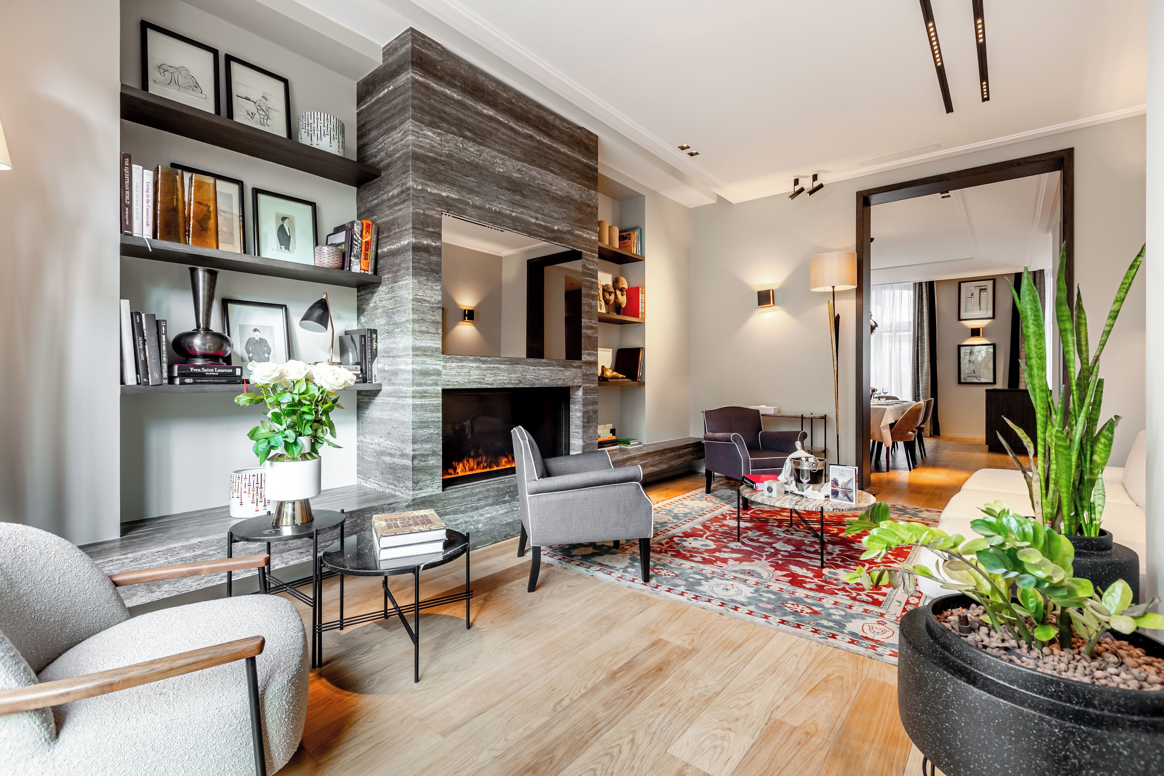 Una sala de estar moderna con chimenea de piedra, asientos cómodos y una estantería.