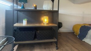 Une pièce avec une étagère en bois foncé, une petite plante en pot, une bougie allumée et une lampe.
