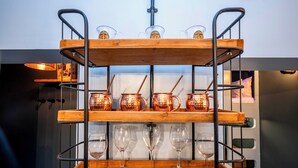 Une étagère en bois à plusieurs niveaux, ornée de chopes en cuivre et de verres à vin.
