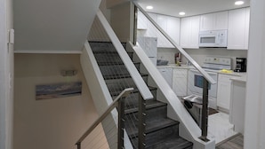 A modern kitchen with white cabinets, a stainless steel staircase, and a microwave. - Oceanfront 2br/2b, in Port Canaveral, Heated Pool & Spa, Ocean Views (Cape Canaveral)