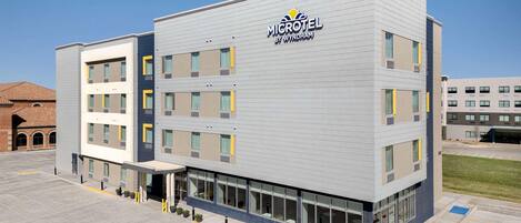 A Microtel hotel by Wyndham with a modern design, multiple floors, and a parking lot.