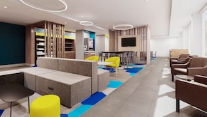 Espaço lounge moderno com assentos, bar e televisão.