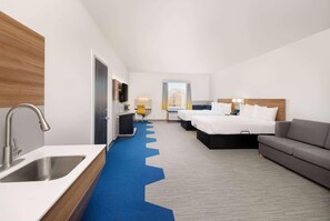A hotel room with a modern design, featuring a large bed, a sofa, a desk, and a bathroom with a sink and mirror. - Microtel Inn & Suites By Wyndham Amarillo West (Amarillo)
