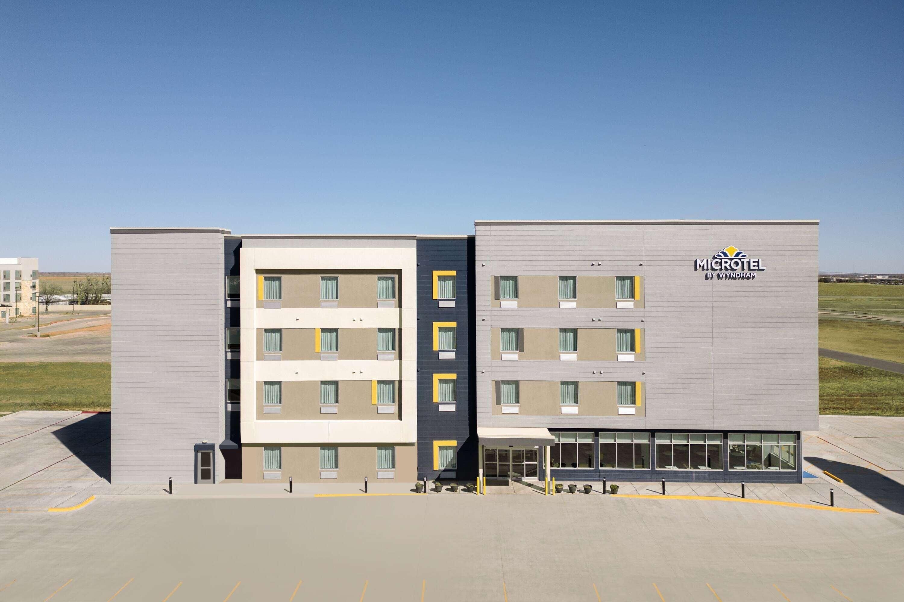 A modern microtel building with a flat facade, multiple windows, and a parking lot in front.