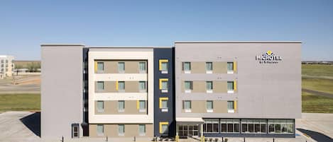 A modern microtel building with a flat facade, multiple windows, and a parking lot in front.