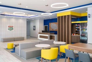 A modern interior with seating, tables, and a refrigerator stocked with beverages. - Microtel Inn & Suites By Wyndham Amarillo West (Amarillo)