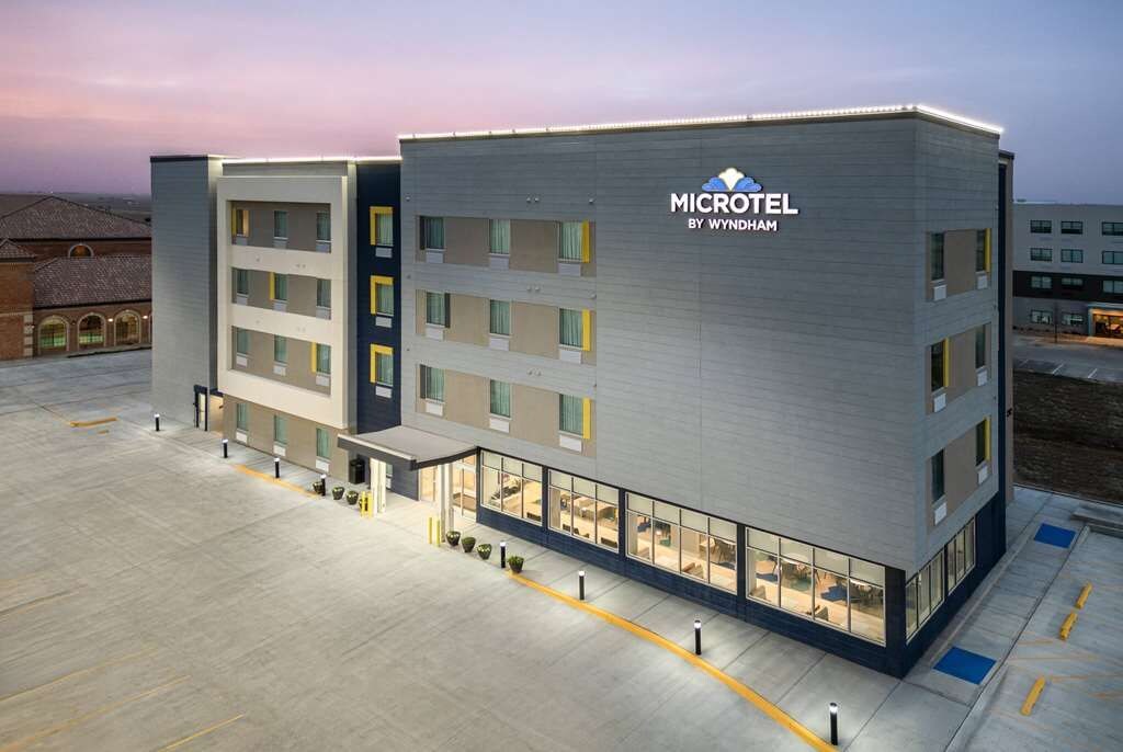 Un microhotel moderno con fachada plana, varios balcones y un área de entrada espaciosa.