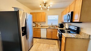 A kitchen with wooden cabinets, a stainless steel refrigerator, a dishwasher, a stove, and a microwave.