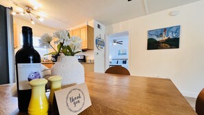 A wooden dining table with a bottle of wine, a vase with flowers, and a thank you card.