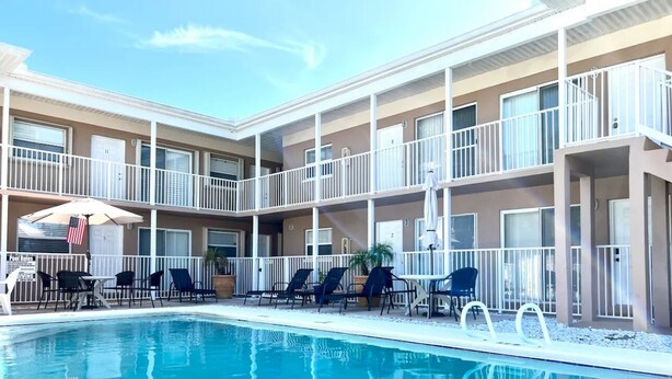 A hotel with a swimming pool, outdoor seating, and balconies.