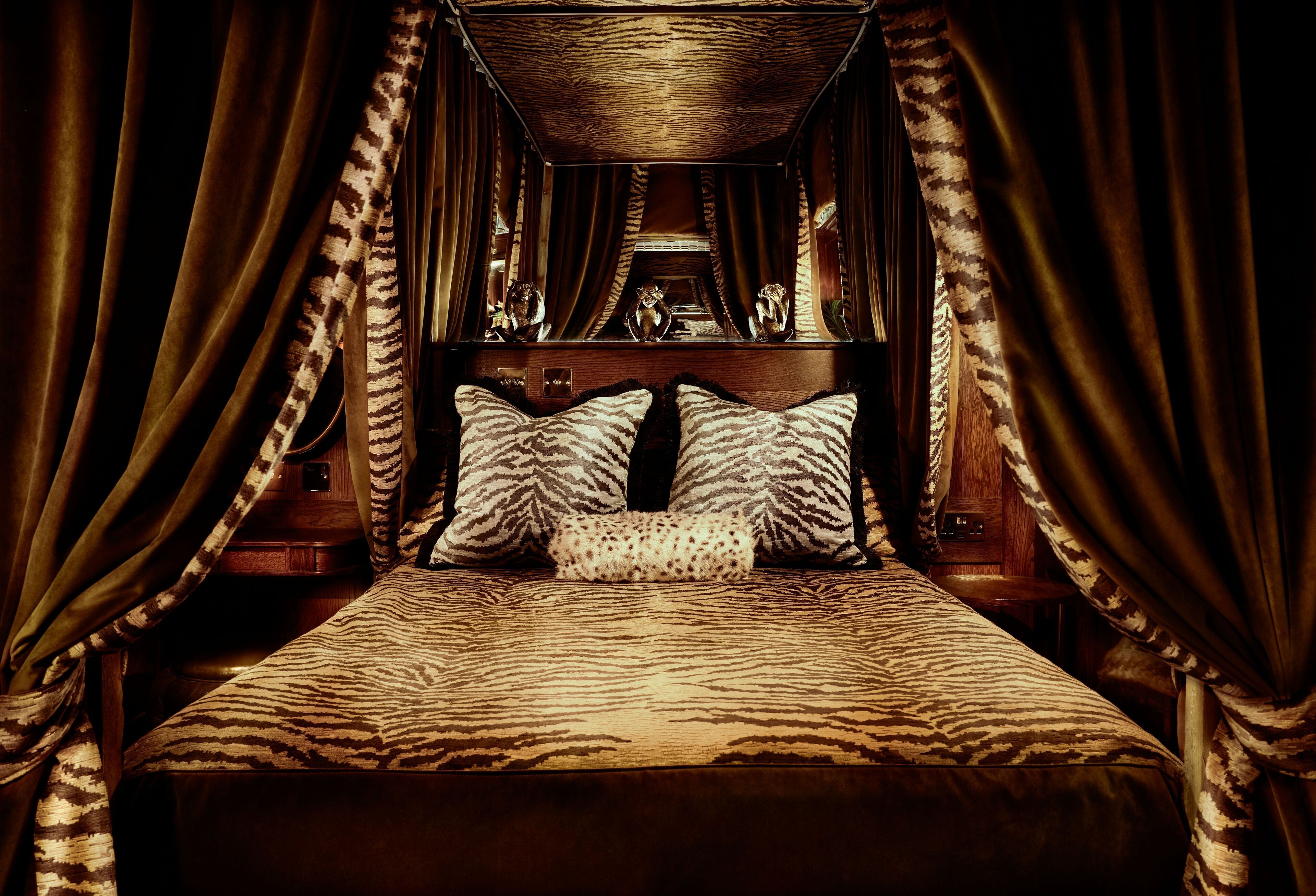 Una cama con ropa de cama estampada de cebra, un cabecero de madera y cortinas a juego.