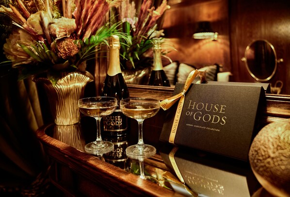 Uma área de bar com garrafas de vinho, copos e uma caixa para doações de chocolate.