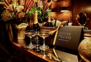 A bar area with bottles of wine, glasses, and a chocolate collection box.
