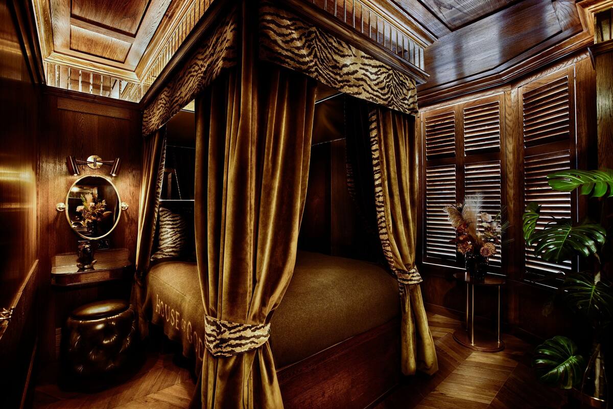 A luxurious bedroom with a four-poster bed, a round mirror, and a wooden vanity.